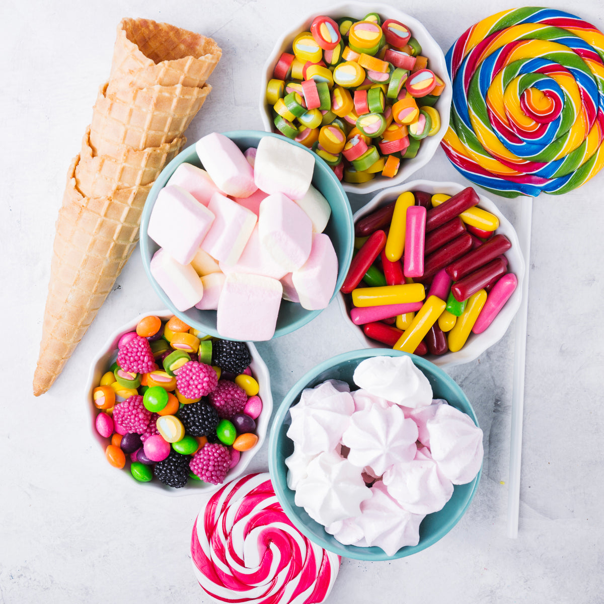 Bunte Auswahl an Süßigkeiten, Marshmallows, Baisers und Waffeln auf hellem Hintergrund